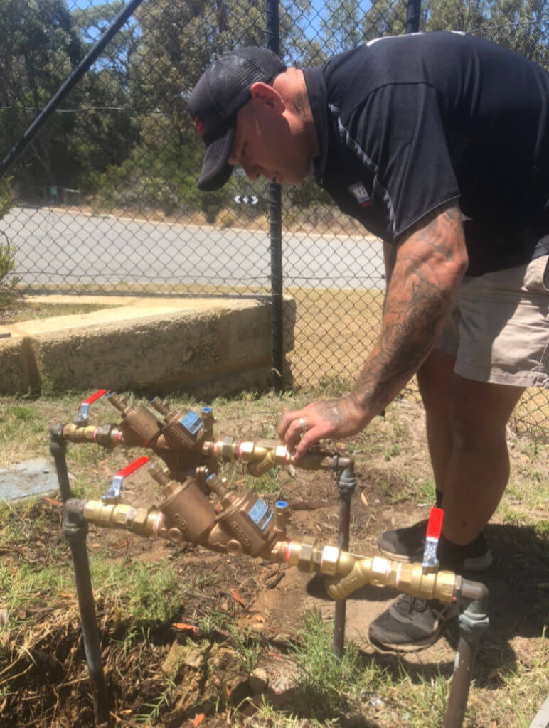 Backflow Prevention Image - Man Making Adjustments on Backflow Controls