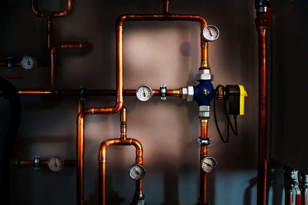 Copper plumbing pipes with multiple pressure gauges and a control valve, part of a gas or water heating system.